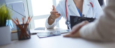 Kadın doktor hastaya danışmanlık yaparken başvuru formu tutuyor