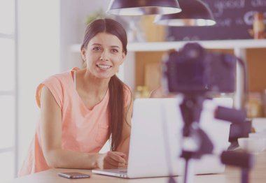 Mutfakta dizüstü bilgisayara benzeyen tariflerle gülümseyen genç bir kadın. Gıda blogcusu kavramı