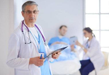 Doktor bir hastanın ve doktorun önünde klasörü tutuyor.