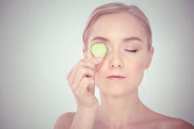 Beyaz zemin üzerine salatalık dilimleri ile genç güzel kadın.