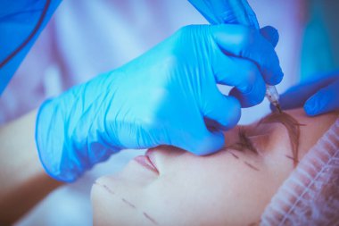 Kaşlar için kalıcı makyaj. Güzellik salonunda kalın kaşlı güzel bir kadın..