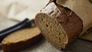 Tahta masanın üzerinde kağıda sarılı bir somun ekmek.