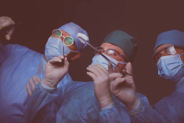 Grupo de cirujanos trabajando en quirófano tonificado en azul. Equipo médico realizando la operación — Foto de Stock