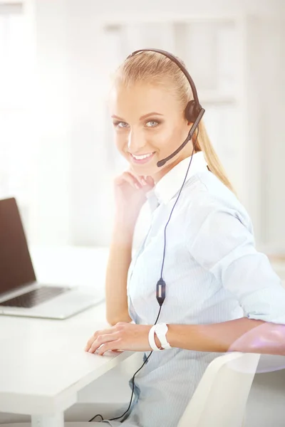 Portret van een lachende receptioniste met laptop en headset op kantoor — Stockfoto