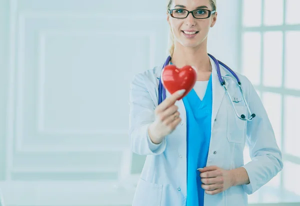 Female doctor with stethoscope holding heart in her arms. Healthcare and cardiology concept in medicine