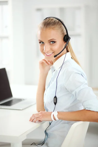 Portret uśmiechniętej recepcjonistki korzystającej z laptopa i zestawu słuchawkowego w biurze — Zdjęcie stockowe