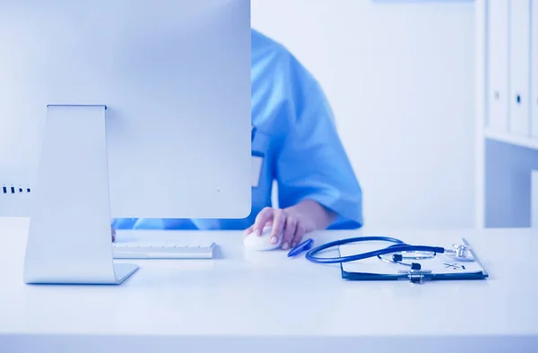 Unbekannte Ärztin füllt ärztliches Formular aus, während sie am Schreibtisch im Krankenhausbüro sitzt — Stockfoto