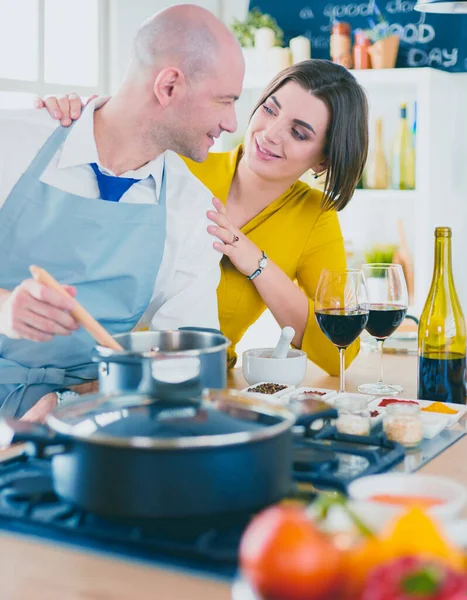 Attractive couple in love cooking and opens the wine in the kitchen while they cook dinner for a romantic evening — Stock Photo, Image