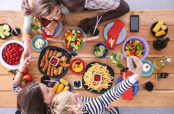 Vista superior del grupo de personas cenando juntas mientras están sentadas en la mesa de madera. Comida en la mesa. La gente come comida rápida. — Foto de Stock