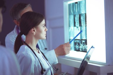 Bir grup doktor bir klinikte röntgenleri inceliyor, teşhis koymayı düşünüyorlar.