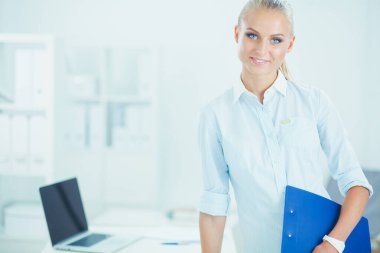 Kağıt klasörile gülümseyen iş kadını portresi, ofiste ayakta