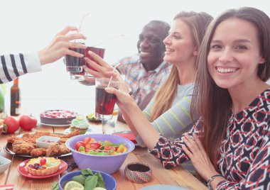 Ahşap masada otururken birlikte yemek yiyen bir grup insanın üst düzey görüntüsü. Masada yemek var. İnsanlar fast food yiyor..