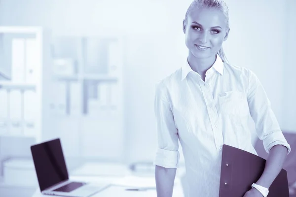Retrato de mulher de negócios sorridente com pasta de papel, de pé no escritório — Fotografia de Stock