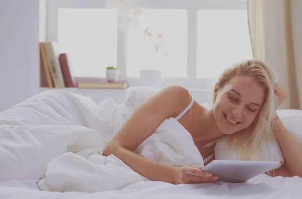 Menina segurando tablet digital com tela em branco e sorrindo para a câmera no quarto — Fotografia de Stock