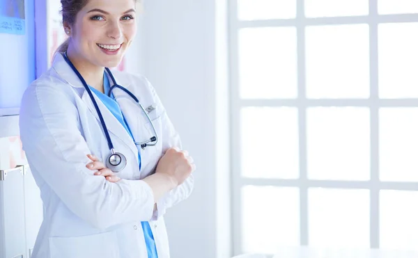 Junge Sanitäterin in weißer Uniform steht in Klinik-Büro — Stockfoto