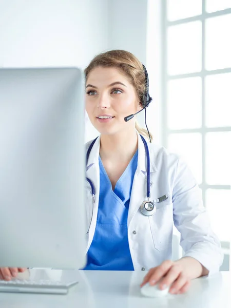 Young practitioner doctor working at the clinic reception desk, she is answering phone calls and scheduling appointments — Stock Photo, Image