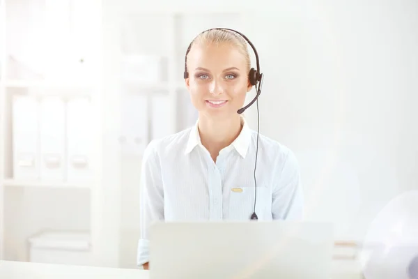 Portrait of pretty young female operator sitting at office desk with headset — Stock Photo, Image