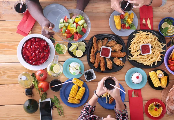 Vue du dessus du groupe de personnes qui dînent ensemble tout en étant assis à une table en bois. De la nourriture sur la table. Les gens mangent fast food. — Photo