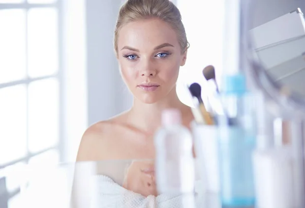 Young woman in bathrobe looking in bathroom mirror — Stock Photo, Image