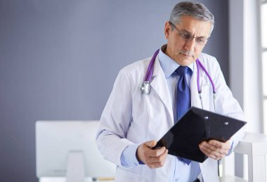 Erkek doktor hastanedeki panoya notlar yazıyor.