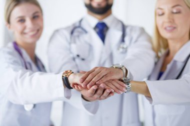 Doktorlar ve hemşireler tıbbi bir ekipte el ele tutuşuyorlar.