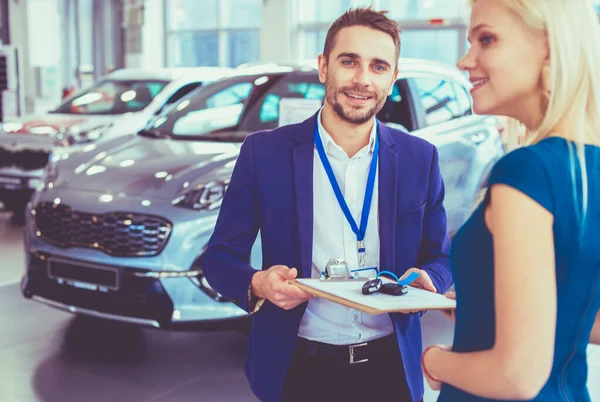 Vendedor de carro vende um carro ao cliente feliz na concessionária de carro e entrega as chaves — Fotografia de Stock