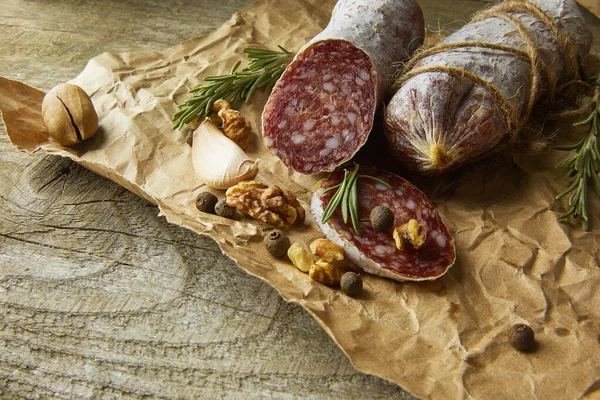 Italienische Salami mit Meersalz, Rosmarin, Knoblauch und Nüssen auf Papier. Rustikaler Stil. Ansicht von oben. — Stockfoto