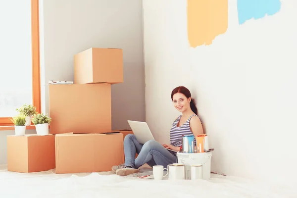 Fiatal nő portréja, új lakás, ül a laptop festés közben. Fiatal nő, laptop — Stock Fotó