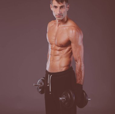 Yakışıklı kaslı adam dumbell ile çalışma dışarı. Kişisel fitness eğitmeni. Kişisel eğitim.