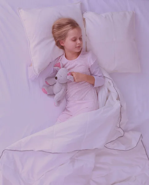 Child little girl sleeps in the bed with a toy teddy bear. — Stock Photo, Image