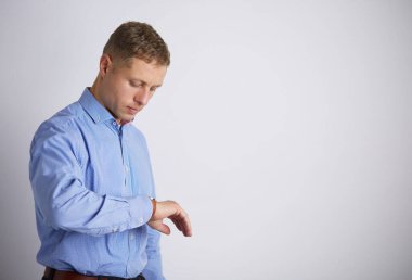 Saate bakan bir iş adamı, gri arka planda izole edilmiş.