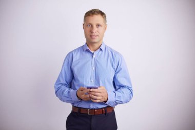 Gülümseyen genç adam akıllı telefonuna bakarken mesajlar gri arka planda izole edilmiş.