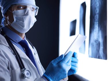 Hastanedeki doktor, beyaz arka plandaki röntgenlere bakıp röntgen çekiyor.