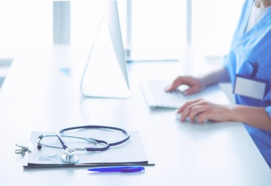 Masada oturan gülümseyen güzel genç bayan doktor.