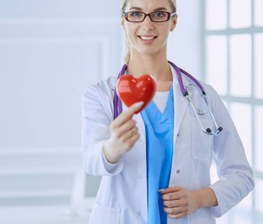 Stetoskoplu kadın doktor kollarında kalp tutuyor. Tıpta sağlık ve kardiyoloji kavramı