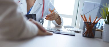 Kadın doktor hastaya danışmanlık yaparken başvuru formu tutuyor