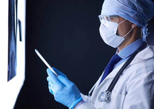 Γιατρός στο νοσοκομείο κάθεται στο γραφείο κοιτάζοντας ακτινογραφίες σε δισκίο σε λευκό φόντο με ακτίνες Χ — Φωτογραφία Αρχείου