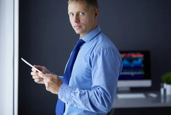 Empresário sorridente com touchpad em pé no local de trabalho no escritório — Fotografia de Stock