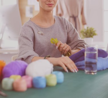 Moda tasarımcıları stüdyoda çalışıyor. Masanın üzerinde oturuyorlar.