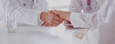 Doktor ofiste erkek bir hastayla el sıkışıyor.