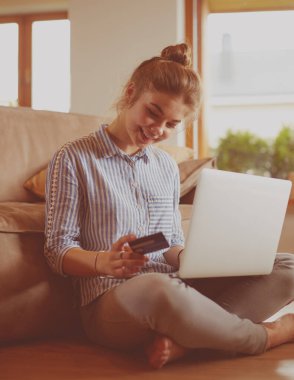Online alışveriş için kredi kartı ve dizüstü bilgisayar kullanan güzel genç kadın
