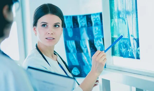 Two smiling doctors pointing at x-rays in a hospital consulting room