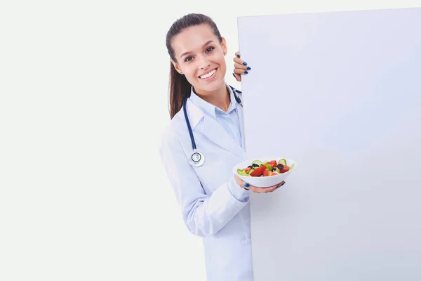Portret van een mooie vrouwelijke arts die een bord met verse groenten in de buurt van leeg houdt. Vrouwelijke artsen — Stockfoto