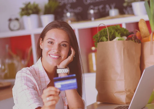 Улыбающаяся женщина онлайн покупки с помощью планшета и кредитной карты на кухне. Улыбающаяся женщина — стоковое фото