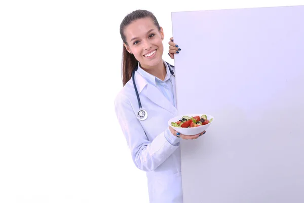 Retrato de una hermosa doctora sosteniendo un plato con verduras frescas en blanco. Mujeres doctores — Foto de Stock