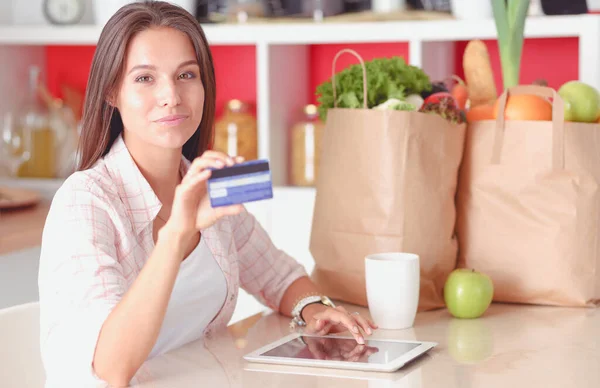 Una giovane donna in cucina, che usa il suo iPad. Giovane donna — Foto Stock