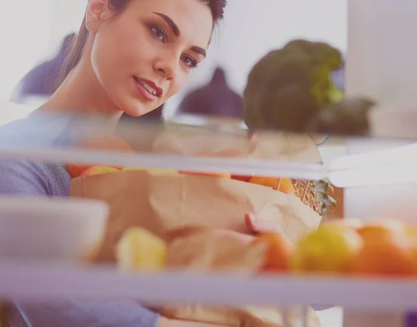 Mosolygó nő vesz egy friss gyümölcsöt ki a hűtőből, egészséges étel koncepció — Stock Fotó