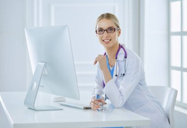 Hastanede masasında oturan genç bir kadın doktorun portresi.