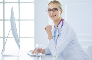 Hastanede masasında oturan genç bir kadın doktorun portresi.