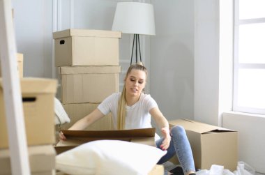 Güzel bekar bir kadın kutuları açıyor ve yeni bir eve taşınıyor. Bir kadın buraya bak tablet